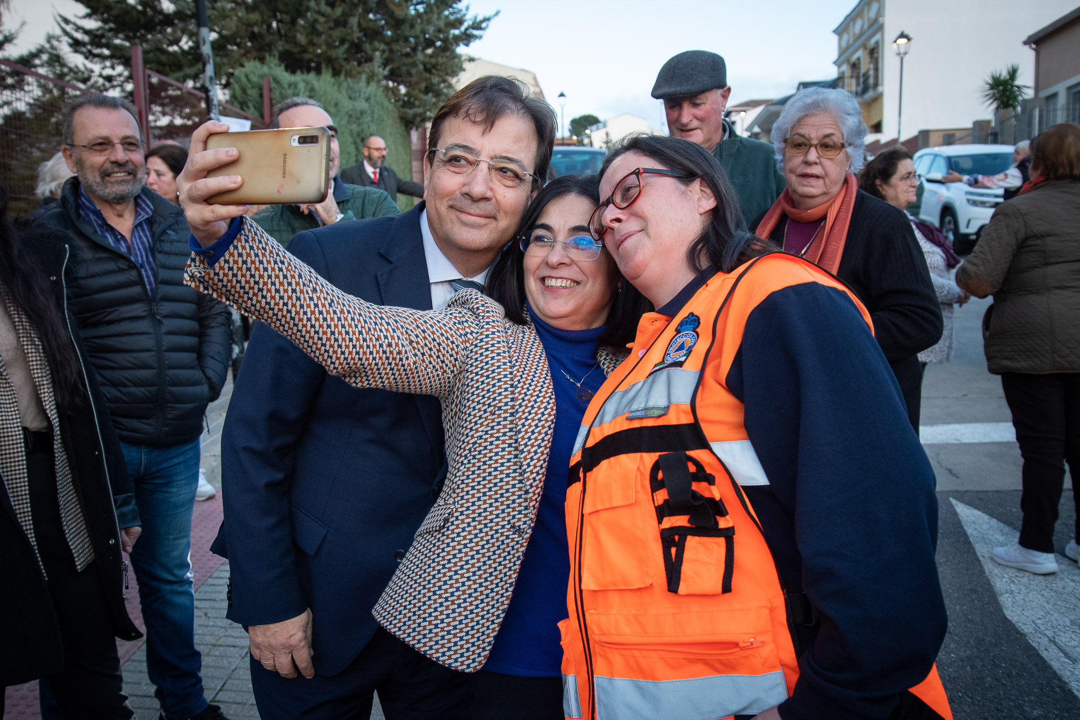 Foto del presidente de la Junta y la ministra de Sanidad haciéndose una foto con un miembro de Protección Civil