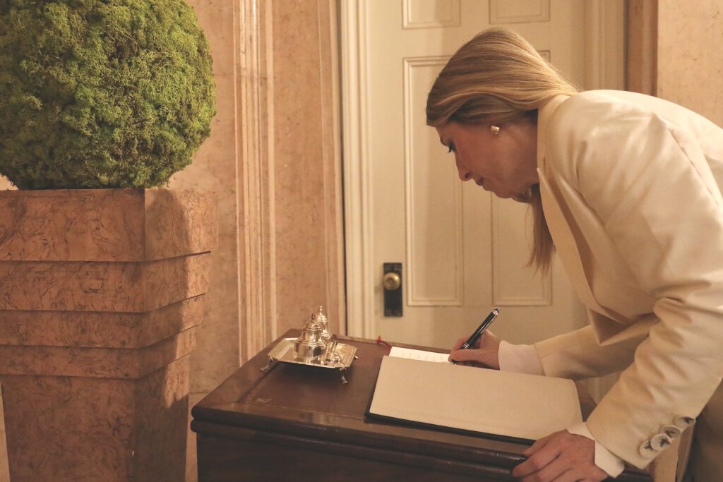 La presidenta de la Junta de Extremadura, María Guardiola, firma en un libro. 